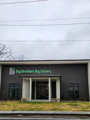 Big Brothers Big Sisters storefront with dark brick facade, white columns, and green sign