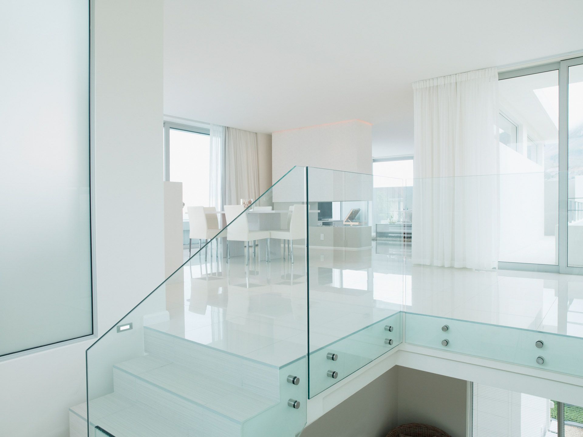 Bright modern interior with glass staircase and white walls