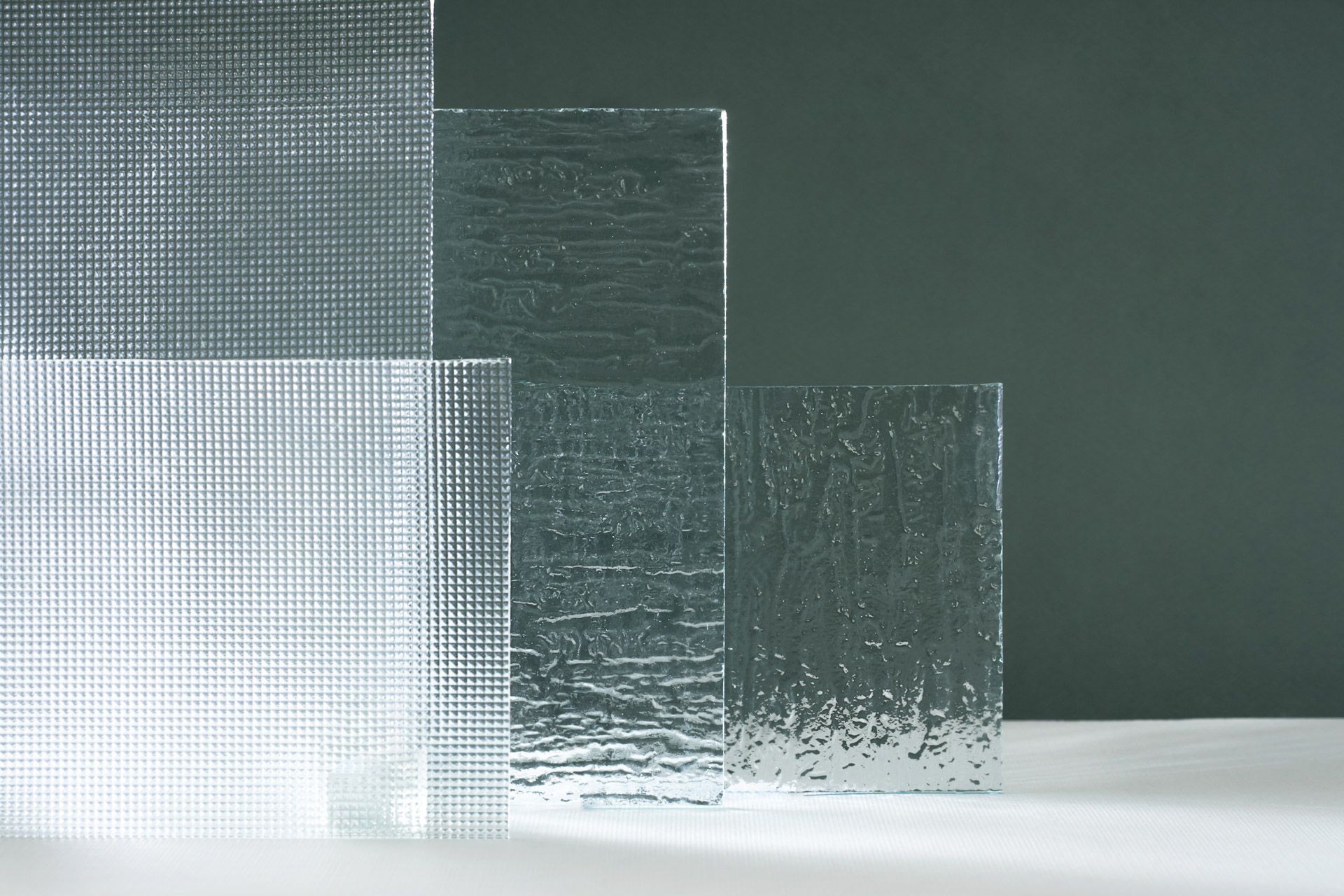 Transparent textured glass blocks on a white surface against a dark green background