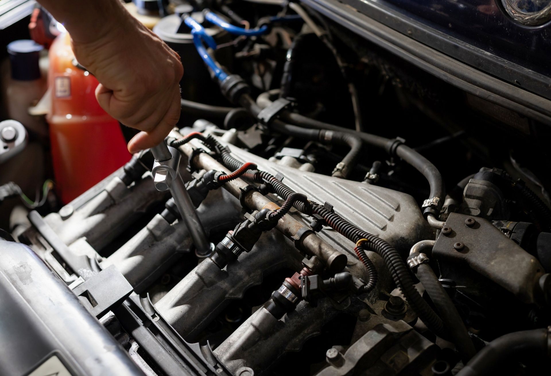 Mechanic's hand inspecting engine components inside a car bay