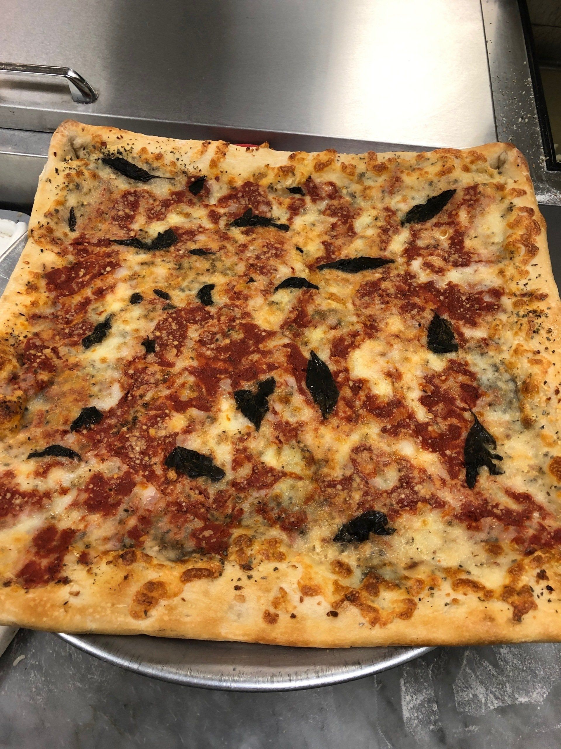 A square pizza with tomato sauce and cheese.
