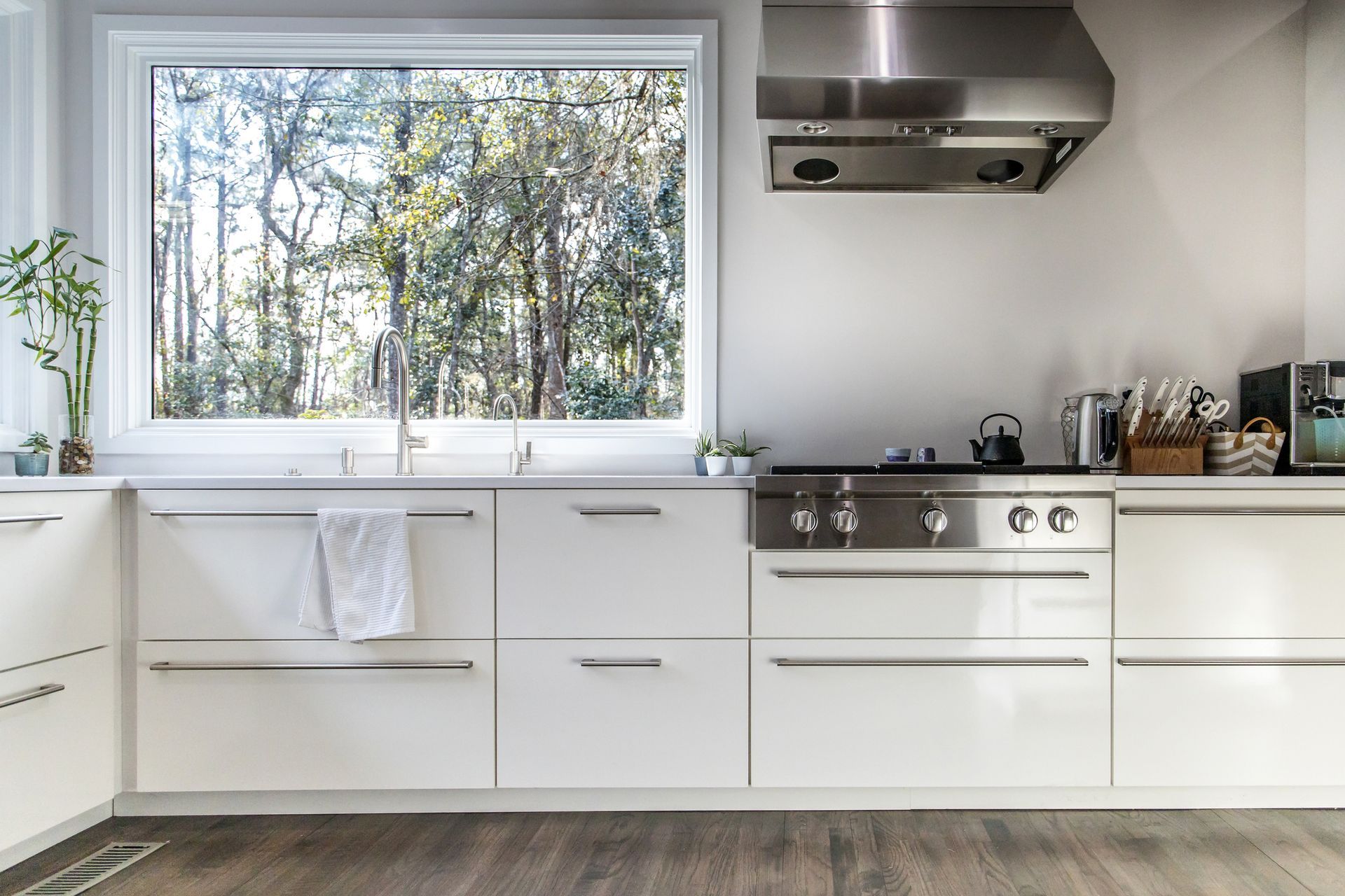 A kitchen with white cabinets and stainless steel appliances and a large window. A kitchen with white cabinets and stainless steel appliances and a large window.