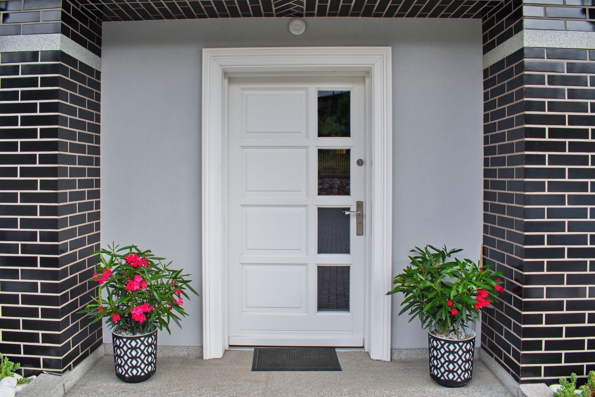A white door with two potted plants in front of it A white door with two potted plants in front of it