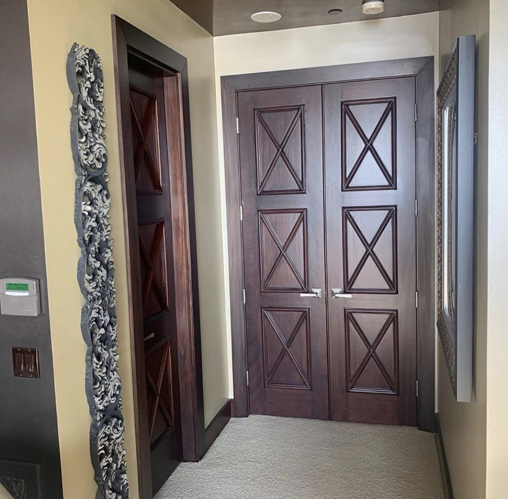 A hallway with wooden doors and a thermostat on the wall