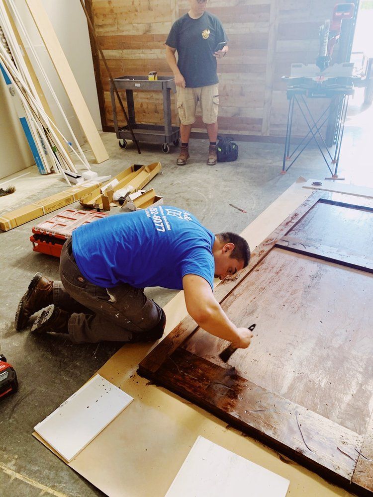 A man in a blue shirt is working on a piece of wood