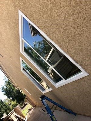 Three windows are being installed on the side of a house.