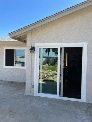 A house with a sliding glass door and two windows.