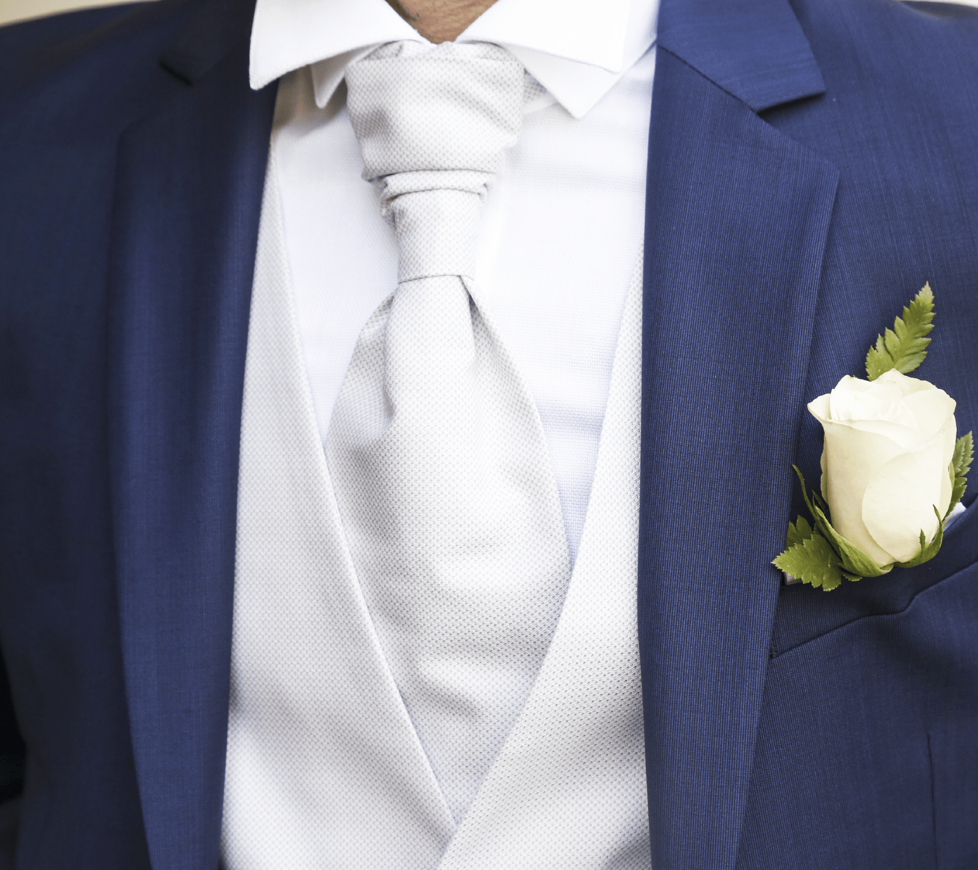 Un uomo in abito blu ha una rosa bianca in tasca