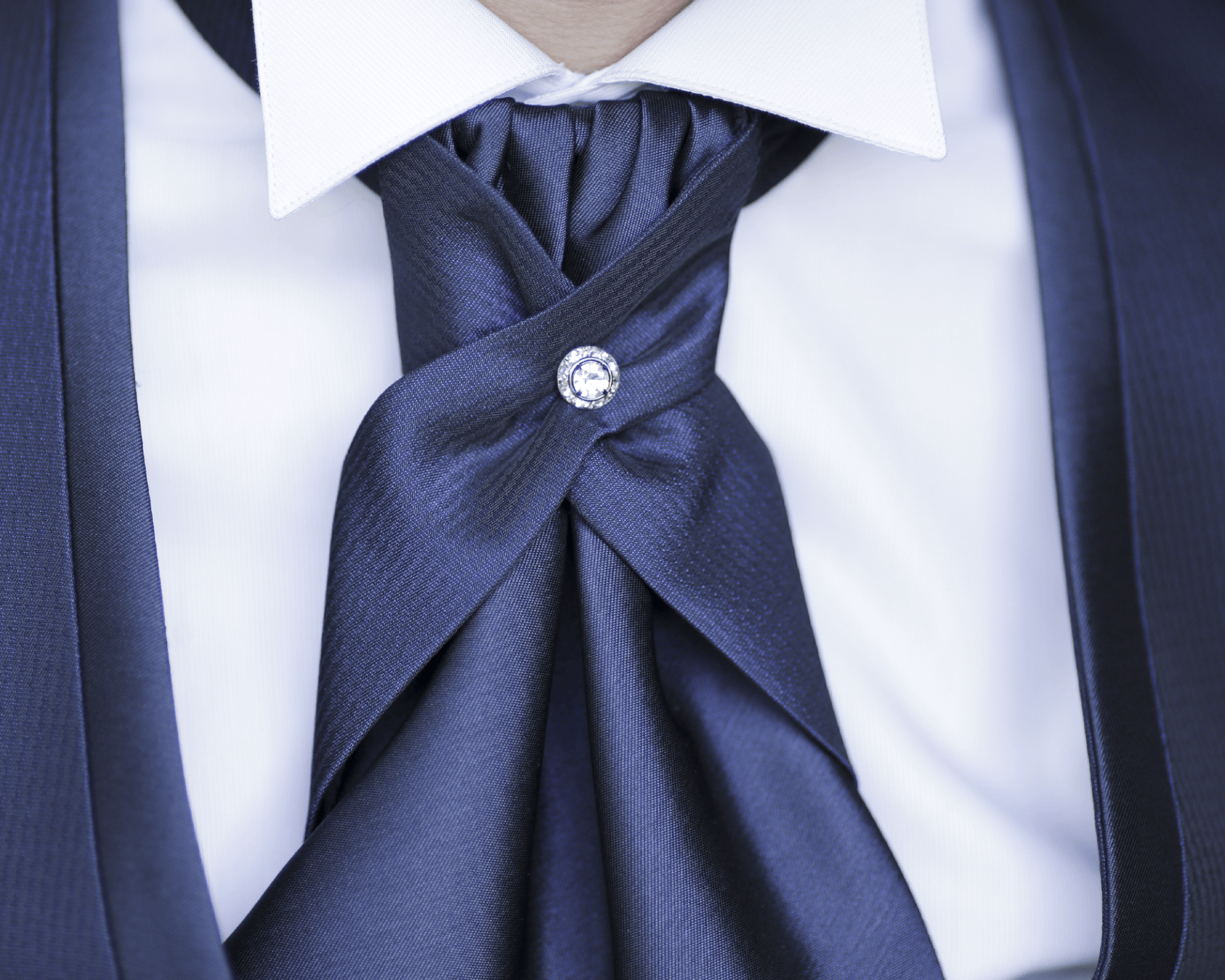 Un uomo che indossa una cravatta blu con una spilla di diamanti