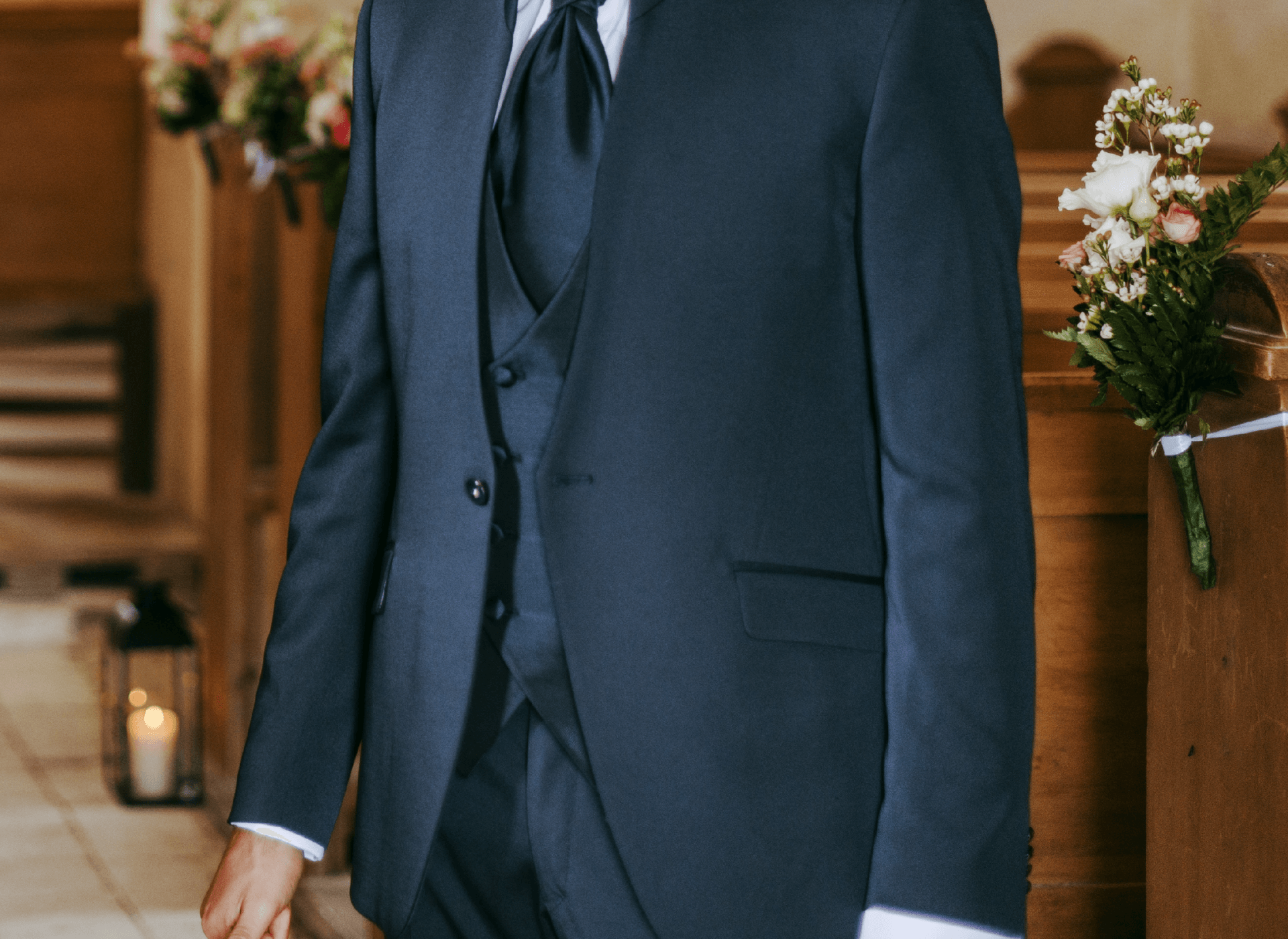 Un uomo in giacca e cravatta cammina lungo la navata di una chiesa.