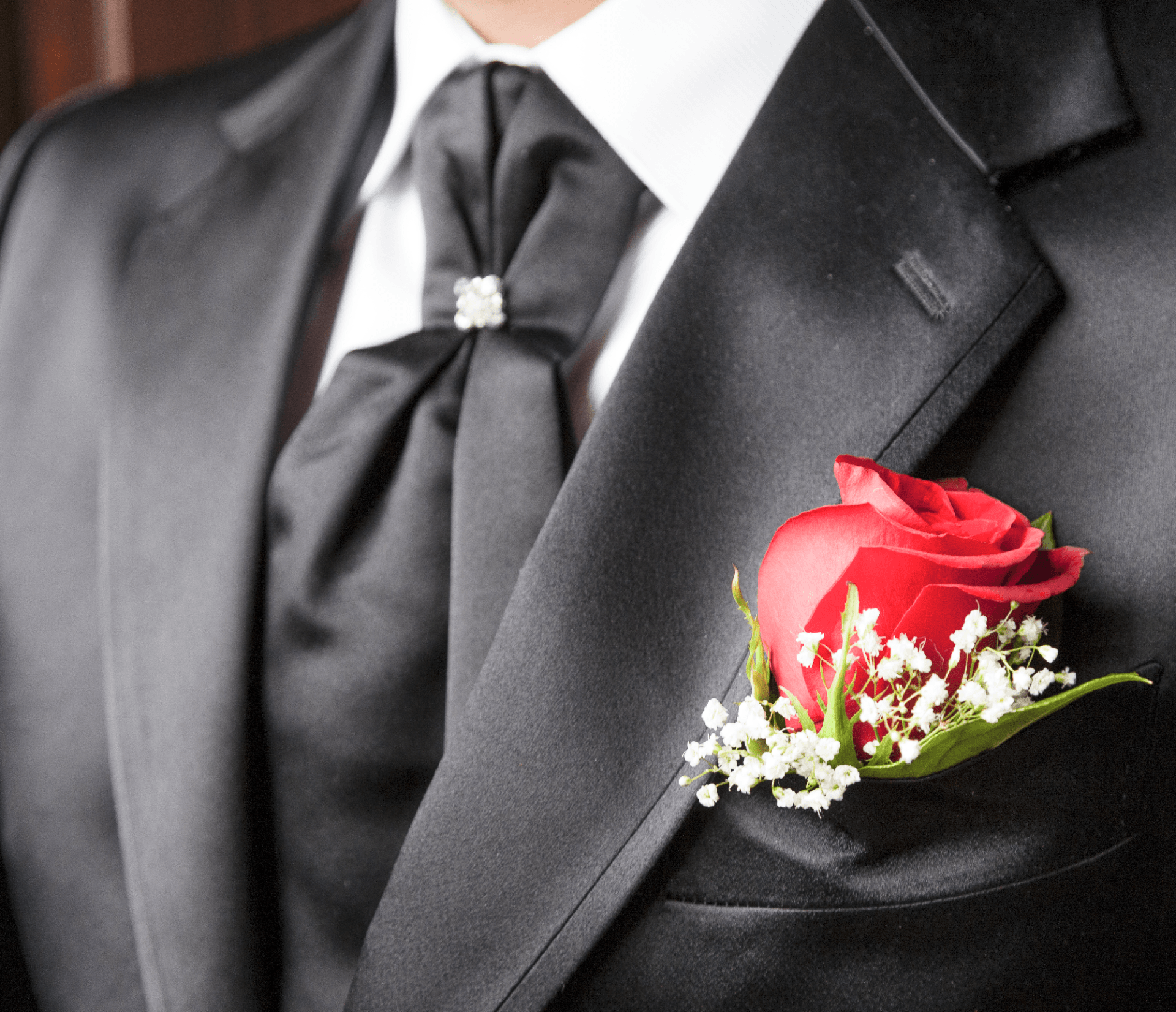 Un uomo in giacca e cravatta ha una rosa rossa in tasca