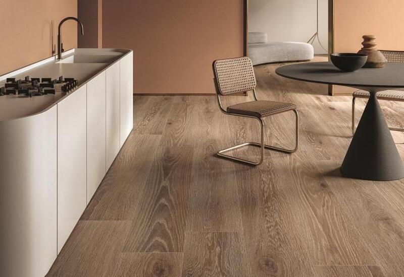 Cucina moderna con pavimento in legno chiaro, isola bianca e tavolo rotondo con sedie.