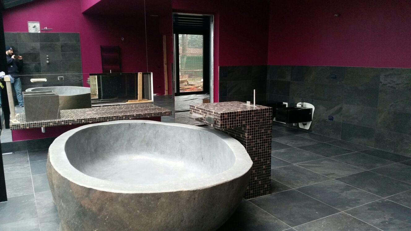 Bagno moderno con un'ampia vasca rotonda da bagno, pavimento in piastrelle scure, pareti color magenta e arredi in tessuto intrecciato.