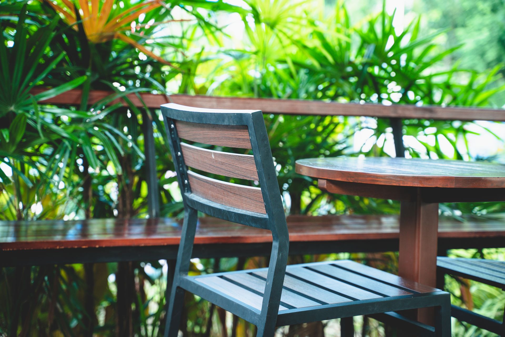 Una sedia di legno vuota accanto a un tavolo in un patio esterno alberato.