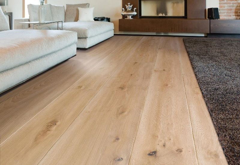 Soggiorno moderno con pavimento in legno chiaro, divani bianchi e tappeto scuro.
