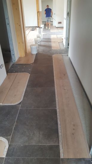 Mani che reggono una piastrella di marmo grigio in uno showroom di campioni per rivestimenti murali e pavimenti.