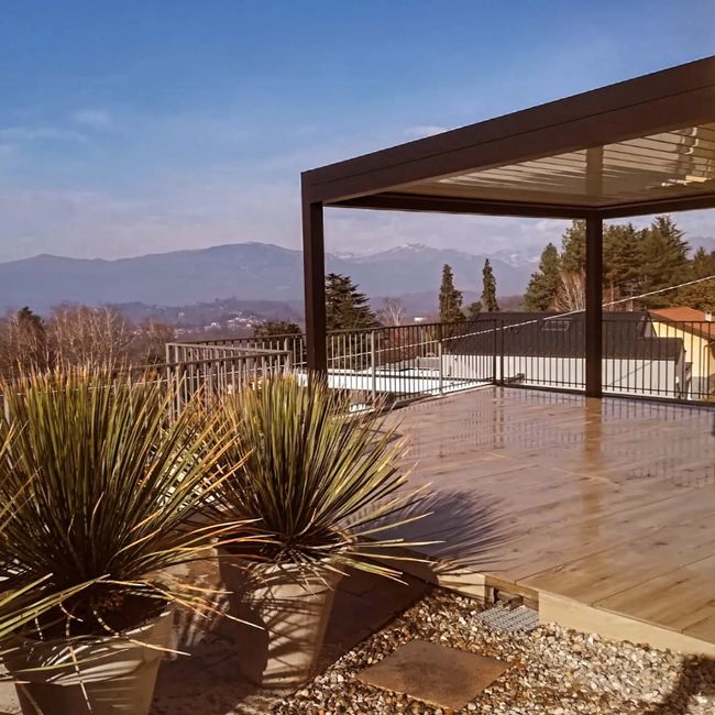 Patio con pergola, piante del deserto in vaso e vista sulle montagne sotto un cielo azzurro limpido.