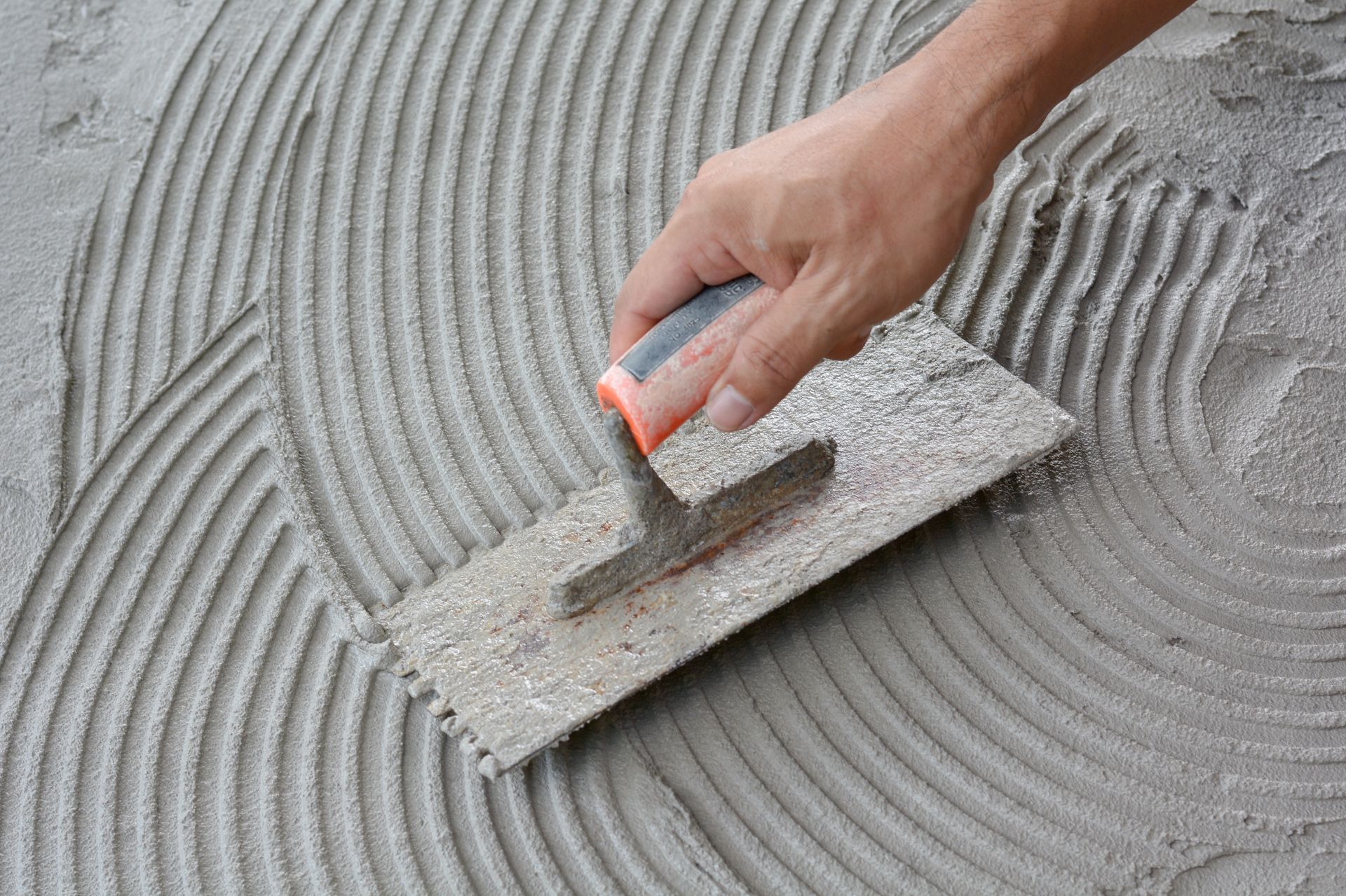 Lisciando a mano l'intonaco grigio ancora umido con una cazzuola, si creano delle scanalature curve.