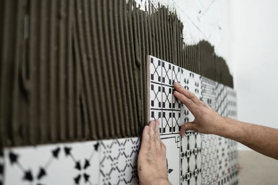 Durante l'installazione, le mani allineano le piastrelle decorate su una parete.