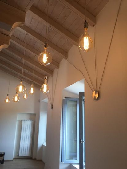 Interno di un loft moderno con pavimento piastrellato in bianco e nero, scala a chiocciola in legno e tavolini da caffè vicino a una finestra.
