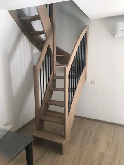Camera moderna con scala a chiocciola, pareti beige e faretti a incasso sul soffitto.