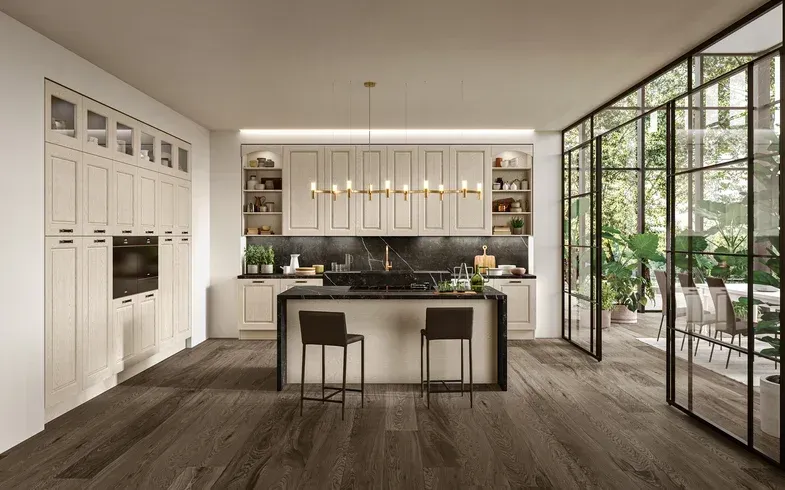 Cucina moderna a pianta aperta con isola, mobili chiari, pavimento in legno e porte finestre a tutta altezza che si aprono su un patio.