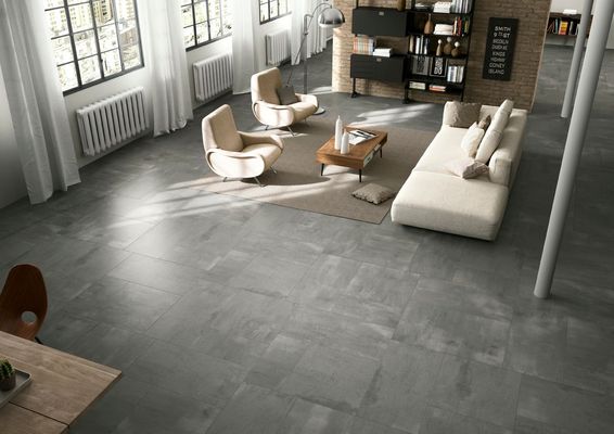 Luminoso soggiorno moderno con pavimento grigio, divano bianco, poltrone, tavolino da caffè e ampie finestre.