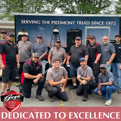 Group of firefighters posing in front of trucks and banner reading “Serving the Piedmont Triad since 1972”
