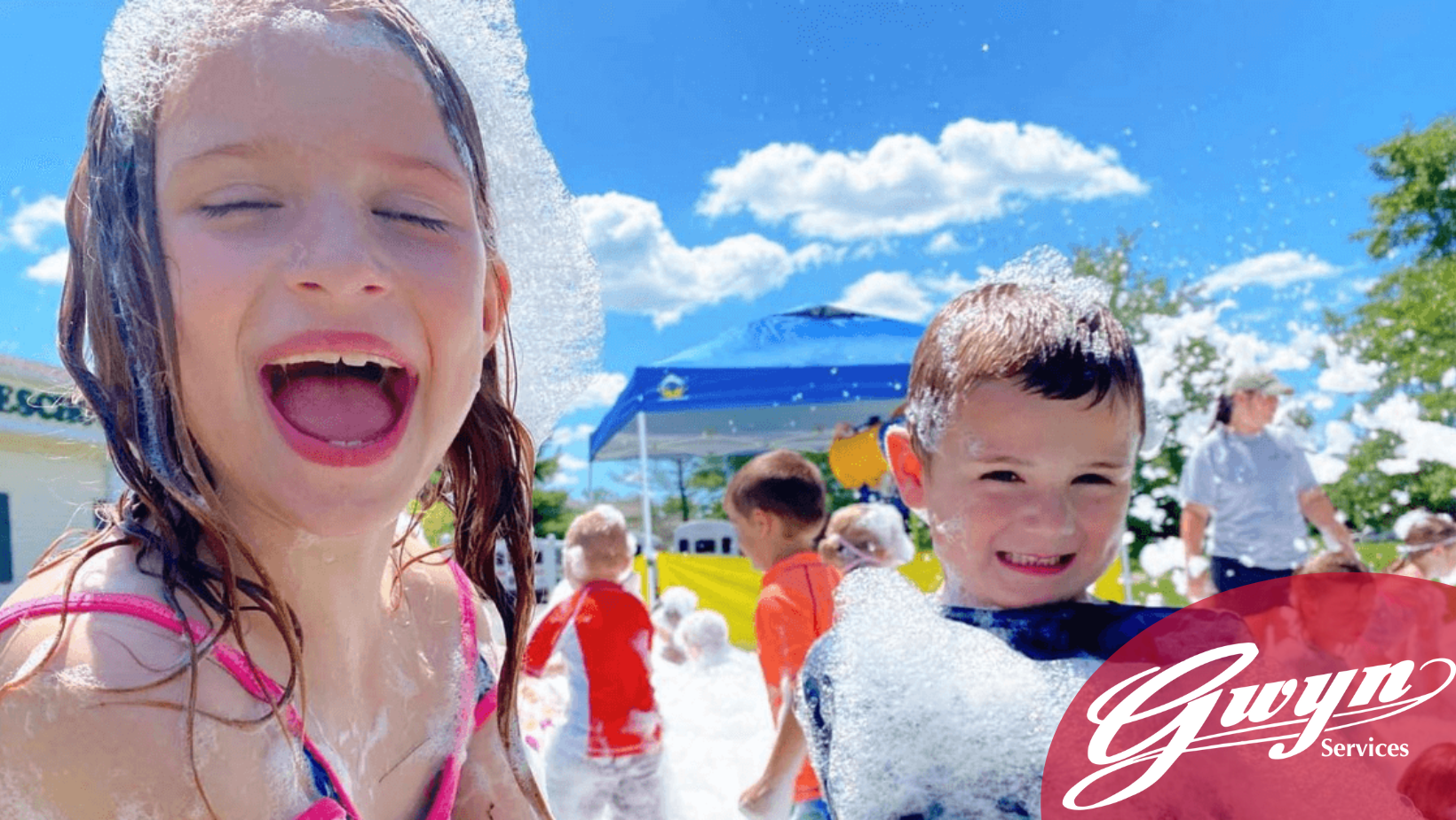 Children playing in a splash pad, laughing under a bright blue sky