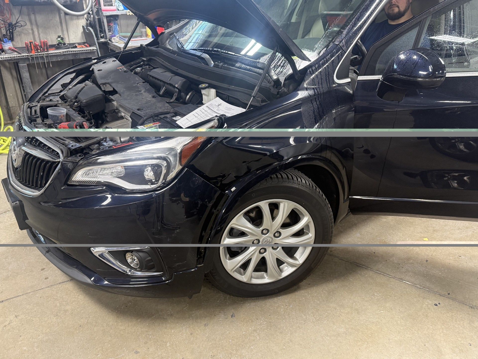 Black SUV in a garage with its hood open and front end exposed during repair.