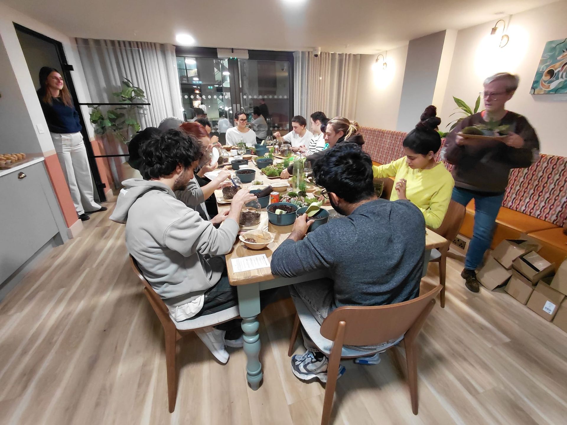 People gathered around a dining table sharing a meal in a bright kitchen or dining room.