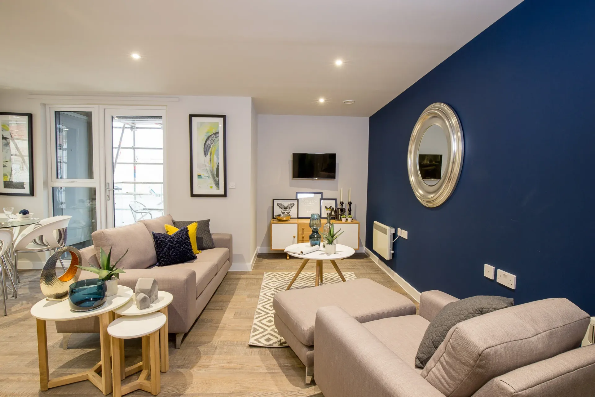 Modern living room with navy accent wall, beige sofas, and bright natural light