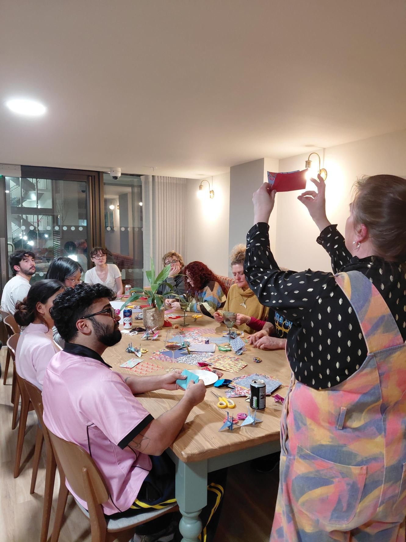People around a dining table, one person photographing a raised cup in a bright room