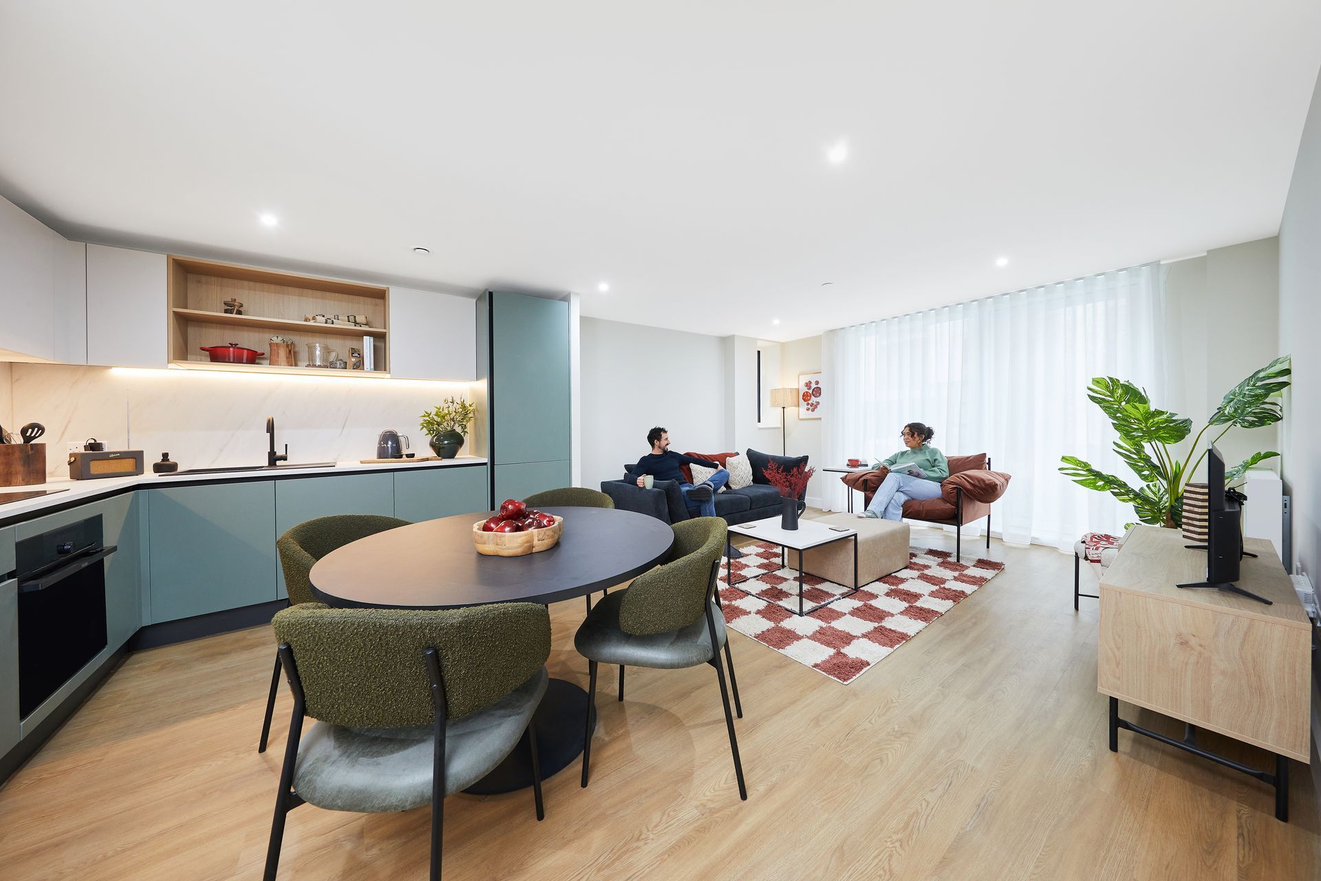 A living room with a dining table , chairs , a couch and a television.