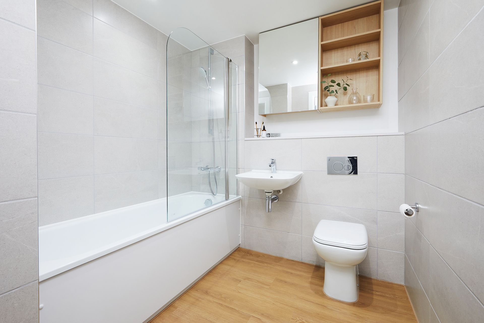 Bright modern bathroom with bathtub, sink, toilet, and light wood accents