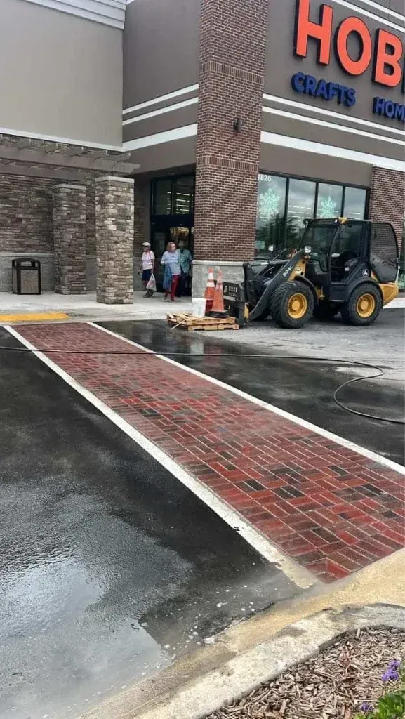 Snowy storefront entrance with a red brick walkway and a construction loader nearby