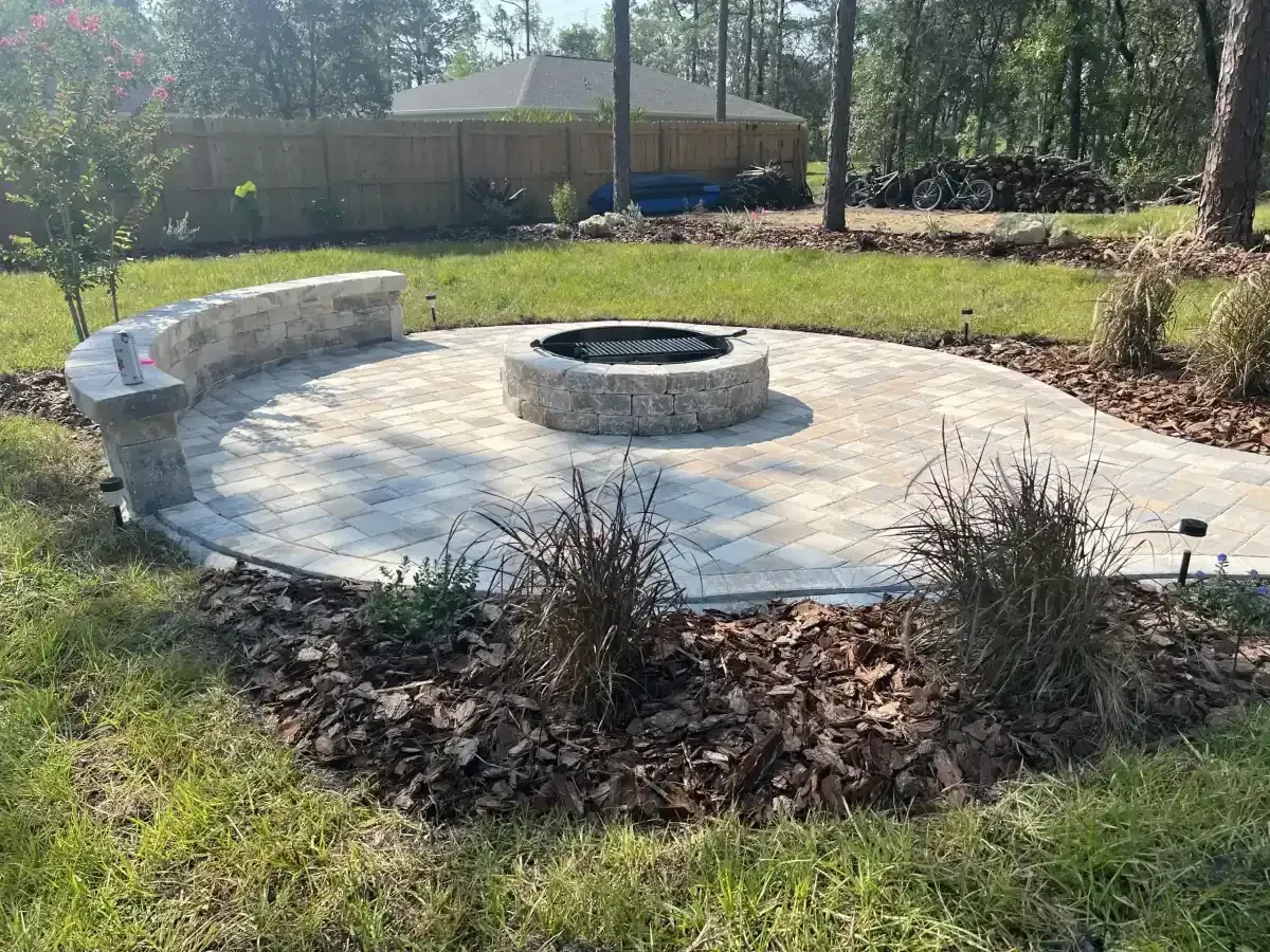 Circular stone fire pit patio with curved bench seating in a landscaped backyard