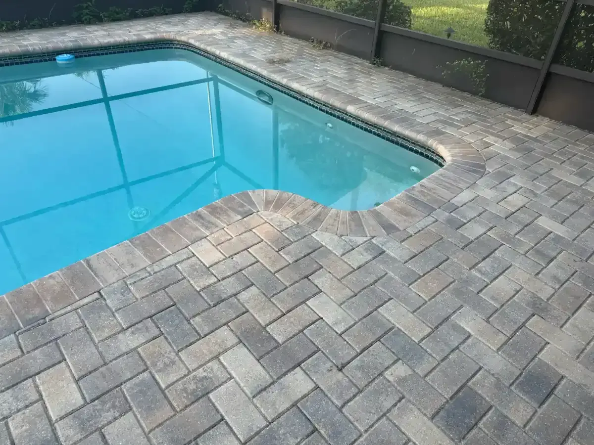 Blue swimming pool beside a gray stone patio and fence area