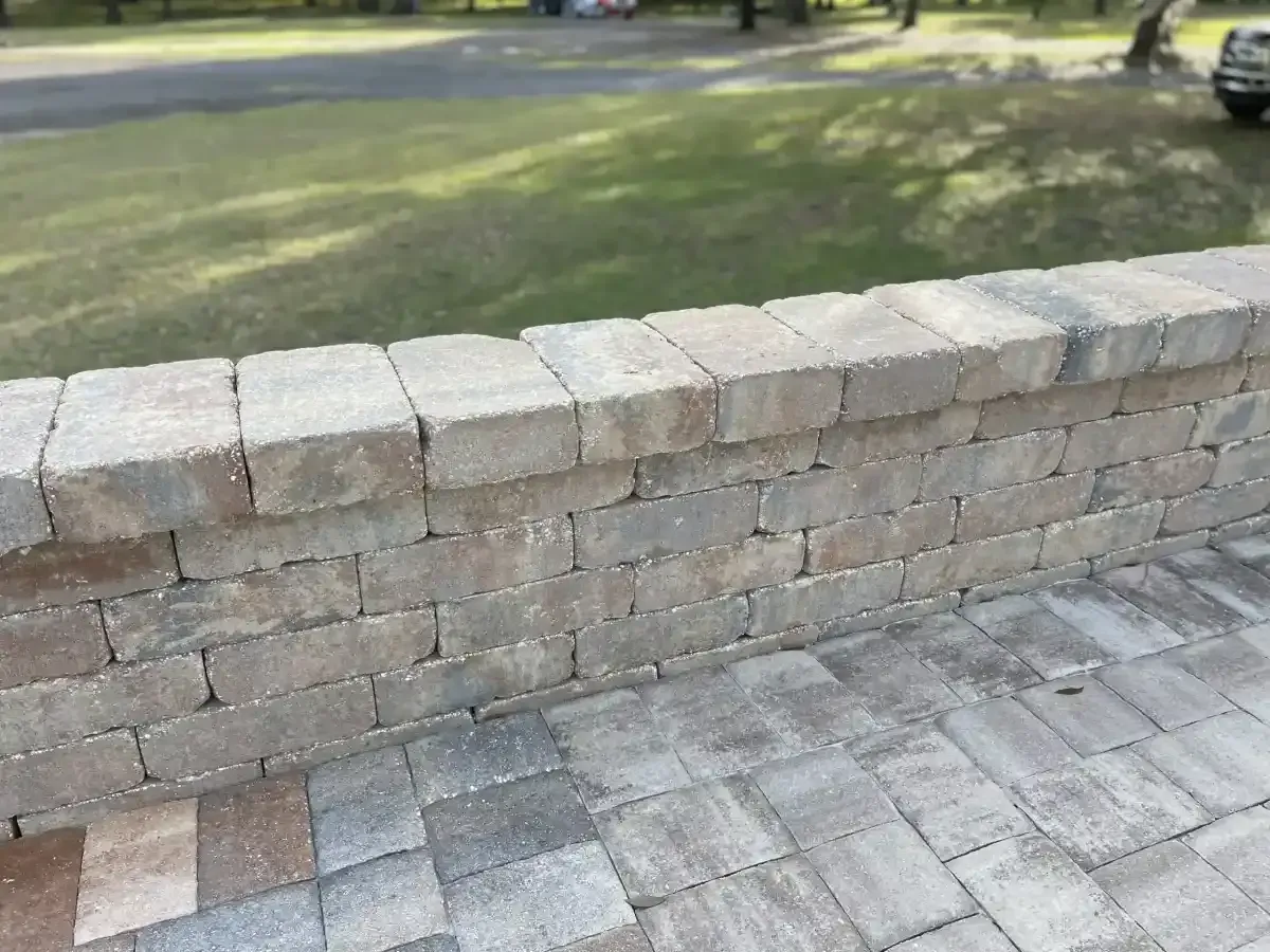 Stone retaining wall beside a paved walkway and grassy park area
