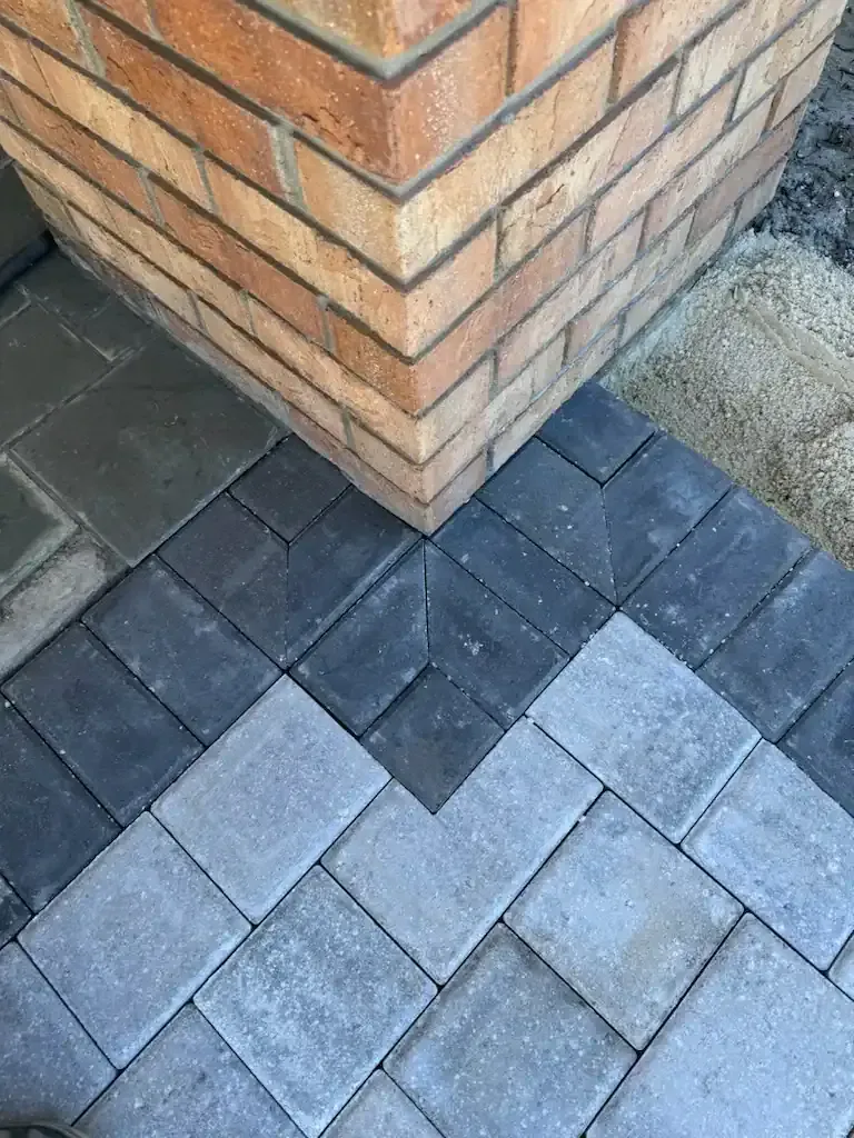 Brick corner beside gray and dark blue paving stones outdoors