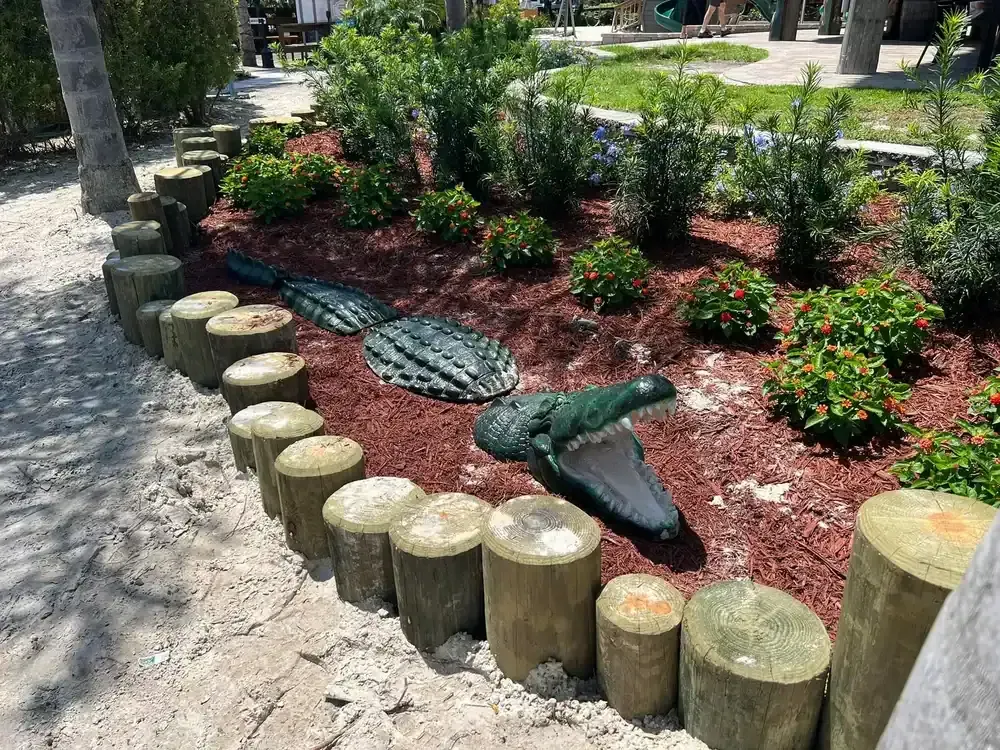 Landscaped garden bed with a decorative fish sculpture and wooden border beside a walkway
