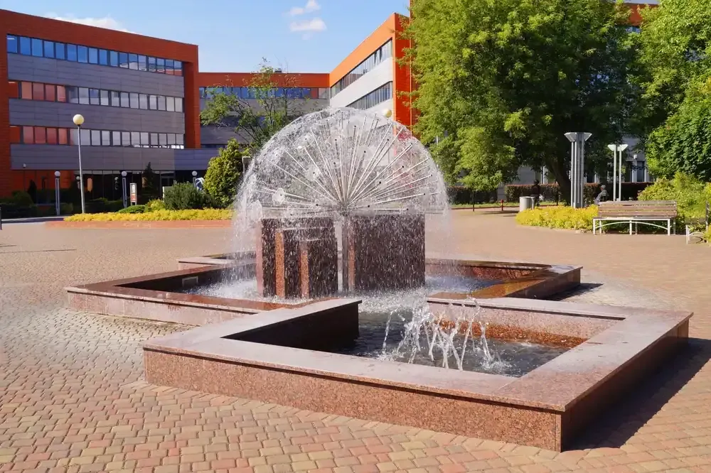 Courtyard fountain with arcing water jets outside a modern brick building
