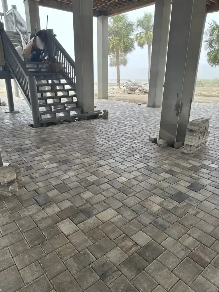 Covered patio with stairs, tiled floor, and beach visible through open columns.