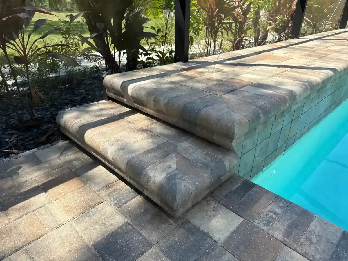 Stone pool steps beside turquoise water in a sunny garden patio