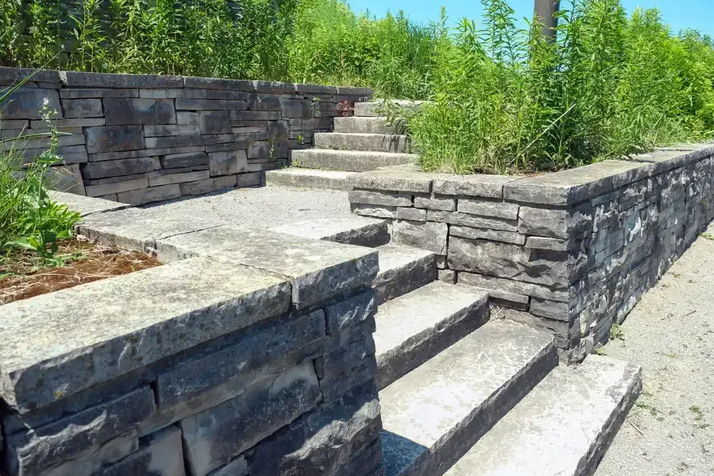 Stone steps and retaining walls on a sunny landscaped hillside path