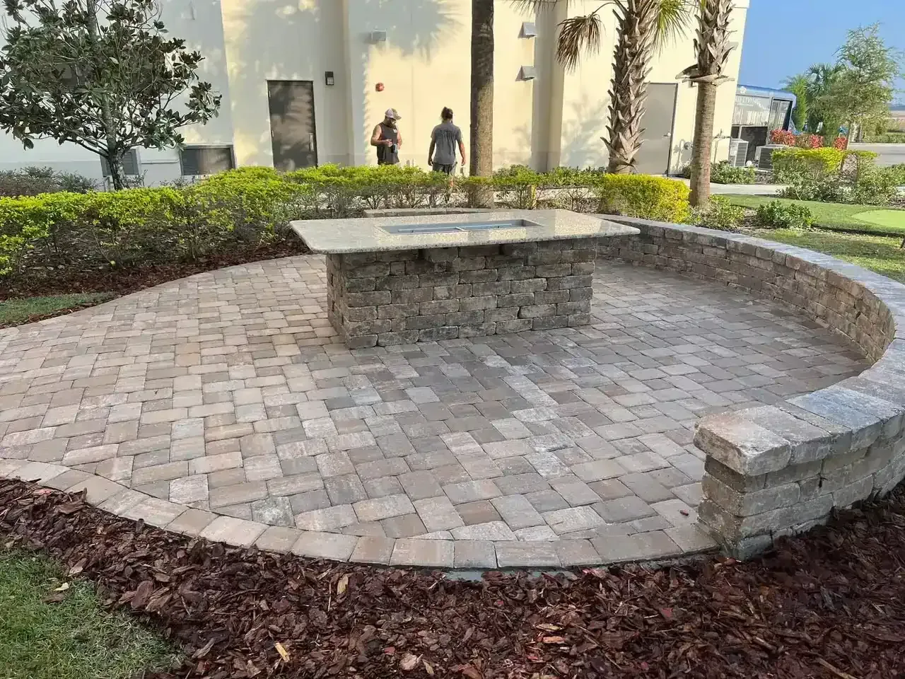 Curved brick bench surrounding a circular paved courtyard in a landscaped outdoor garden