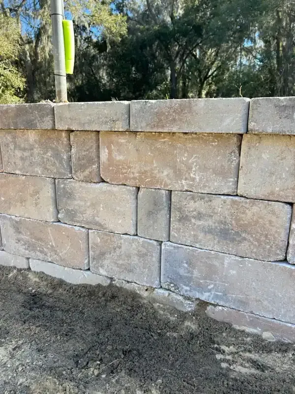 Stone retaining wall beside a gravel path with trees in the background