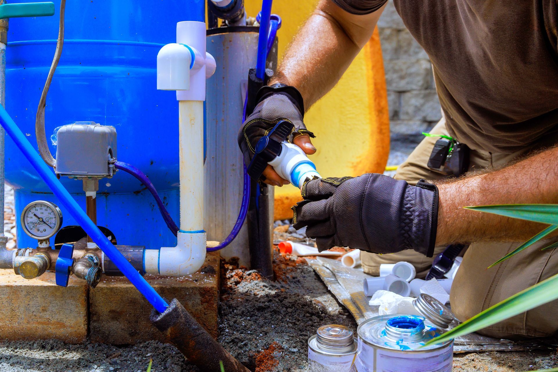 A worker assembling PVC plumbing connections for a water well system. A worker assembling PVC plumbing connections for a water well system.