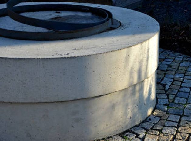 A concrete well sitting on top of a cobblestone walkway. A concrete well sitting on top of a cobblestone walkway.