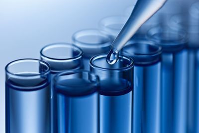 A pipette is pouring liquid into a test tube A pipette is pouring liquid into a test tube